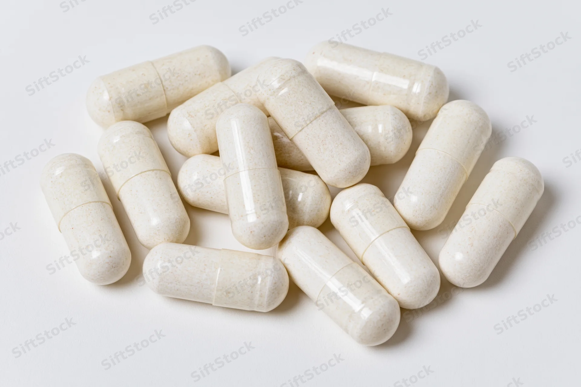 White gelatin supplement capsules scattered loosely on a plain white surface
