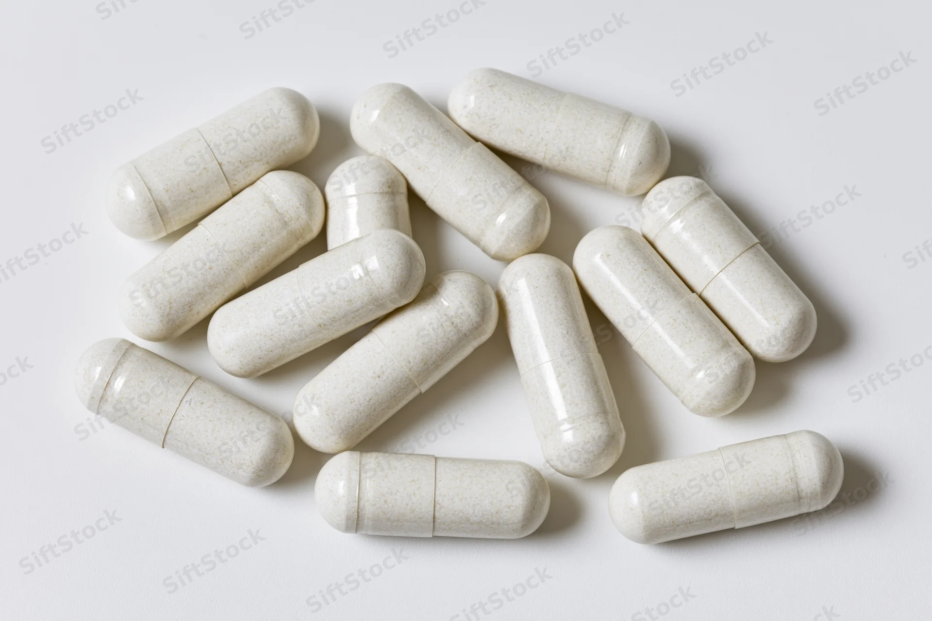 White gelatin supplement capsules scattered loosely on a plain white surface