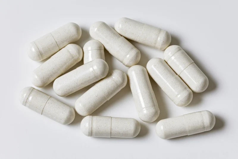 White gelatin supplement capsules scattered loosely on a plain white surface