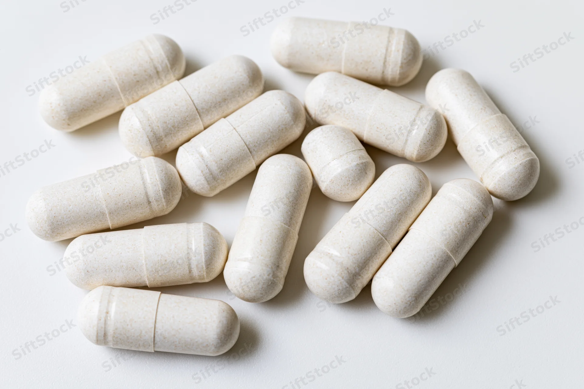 White gelatin supplement capsules scattered on a plain white surface