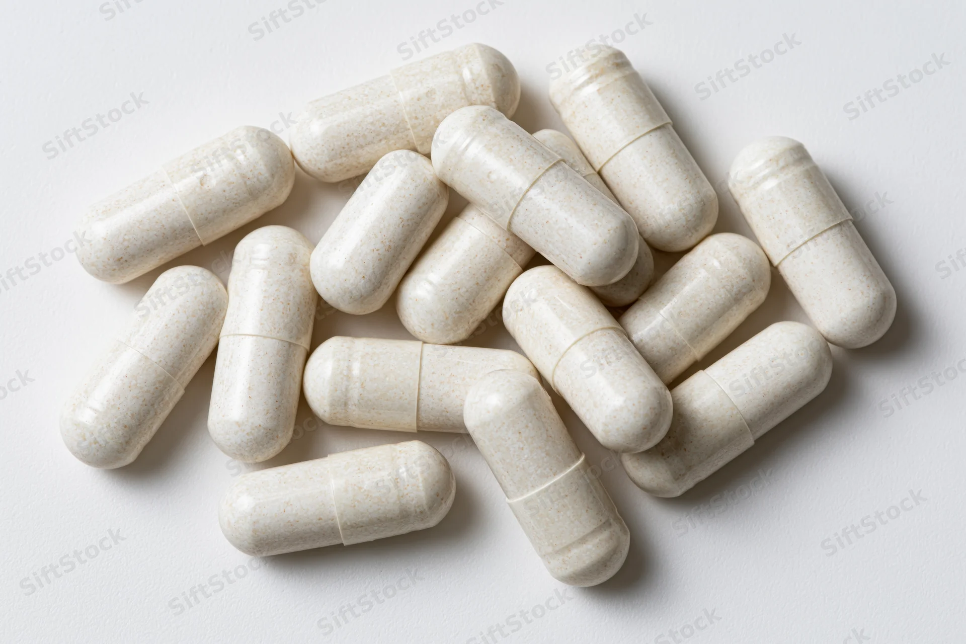 White gelatin supplement capsules scattered loosely on a plain white surface