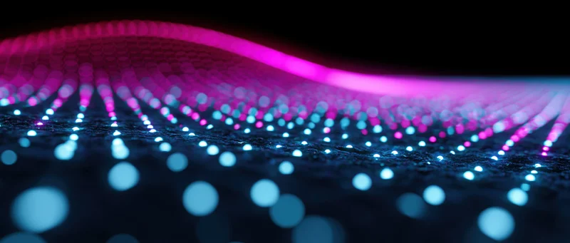 Glowing dot grid forming a wave pattern on a dark surface representing digital data flow