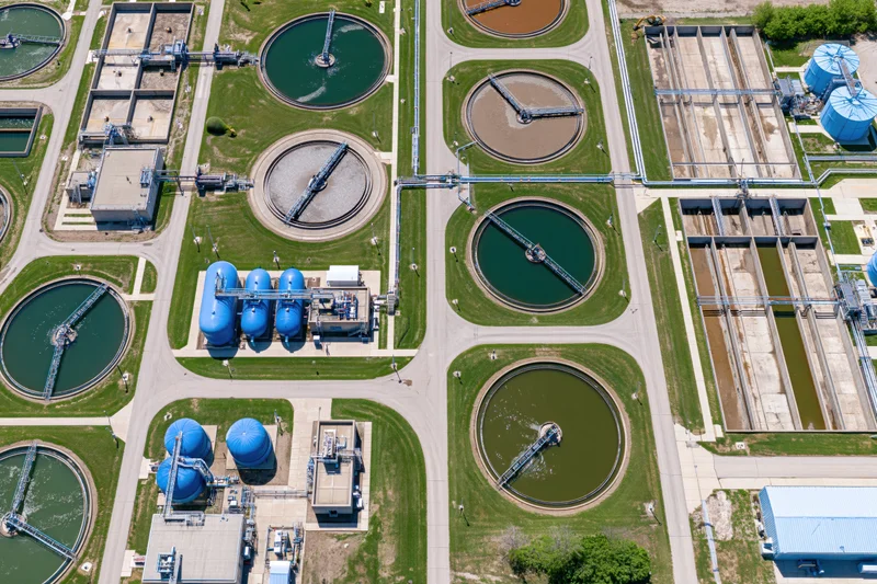 Aerial view of a large water treatment plant with circular tanks and green lawns