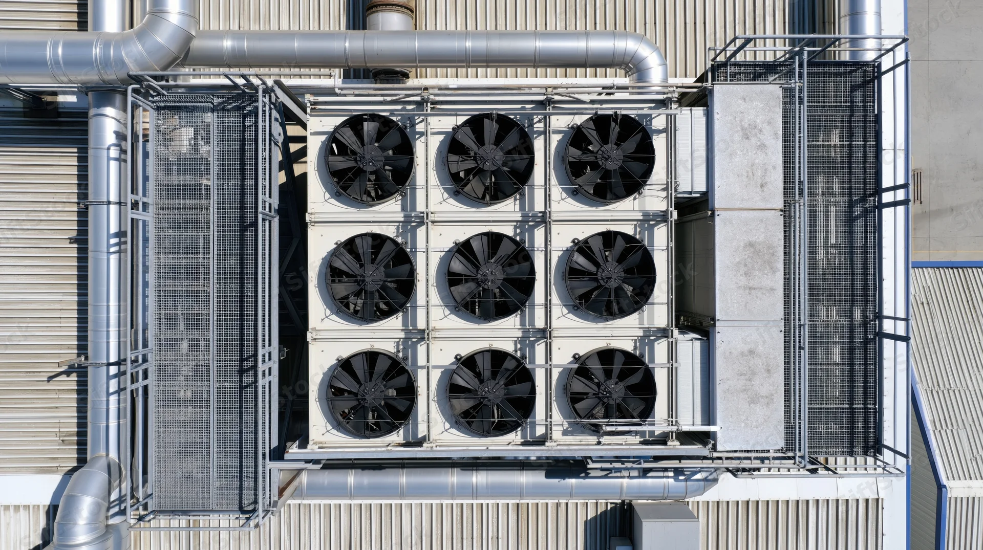 Aerial top-down view of industrial cooling system with fans and ductwork on factory rooftop