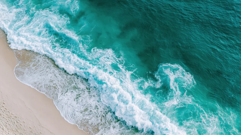 Aerial top-down view of turquoise ocean waves breaking onto a sandy beach