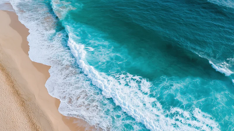 Aerial top-down view of turquoise ocean waves breaking onto a sandy beach
