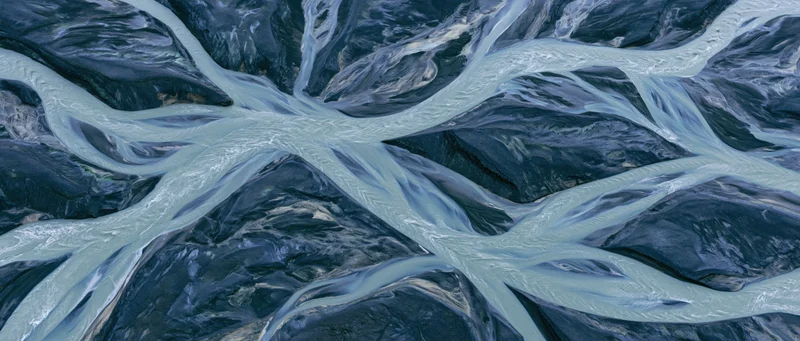 Aerial top-down view of a braided glacial river delta flowing through rocky terrain