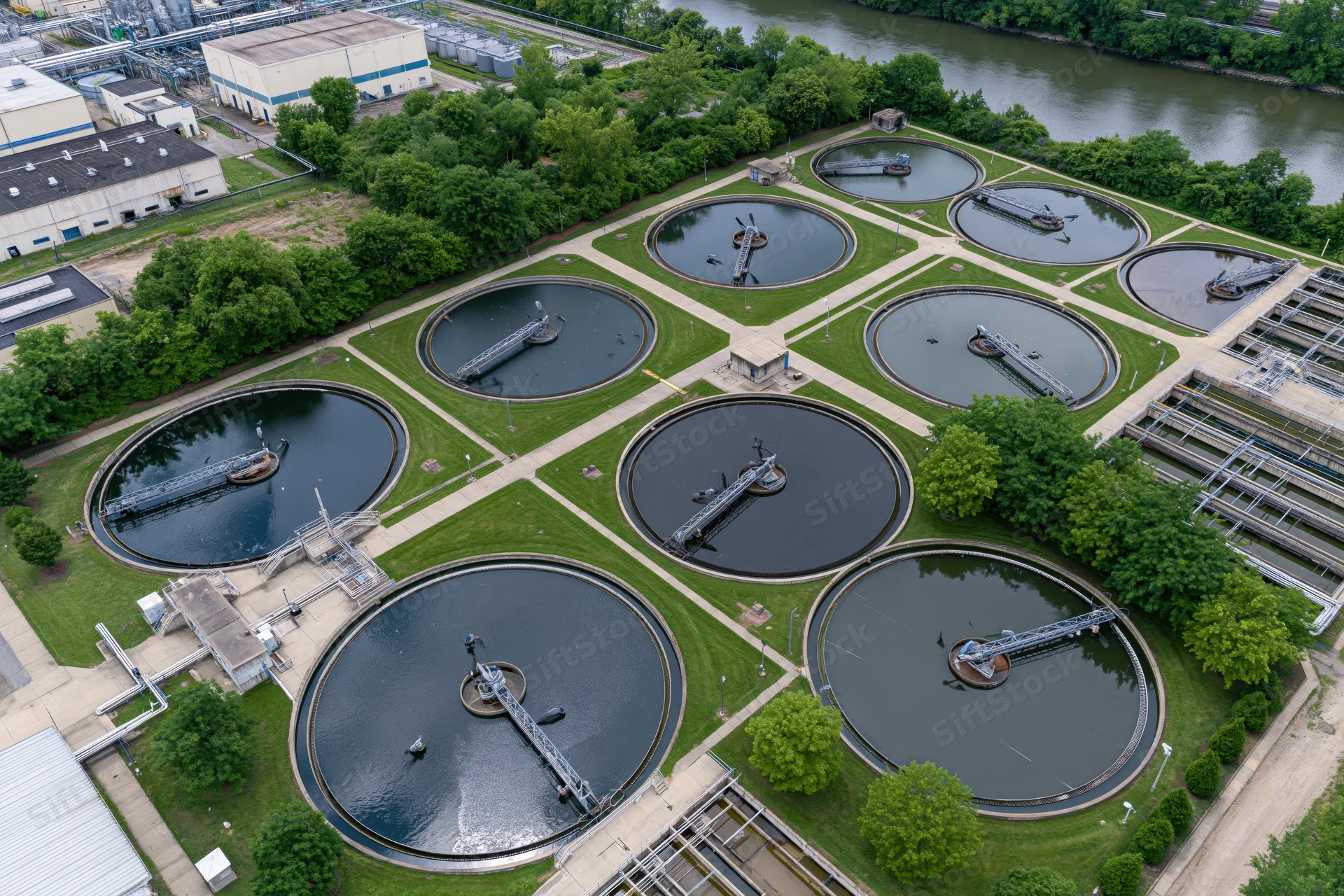 Aerial top-down view of a municipal water treatment facility with circular clarifier tanks and surrounding greenery