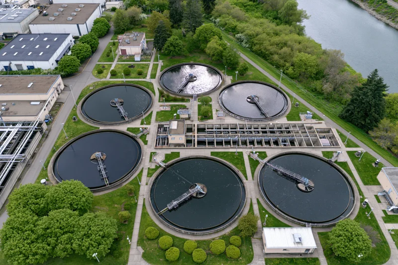 Aerial top-down view of a municipal water treatment facility with circular tanks and surrounding greenery