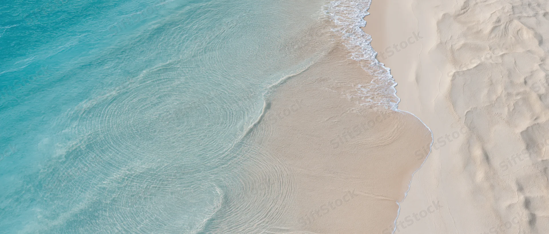 Aerial top-down view of turquoise ocean waves meeting white sand shoreline