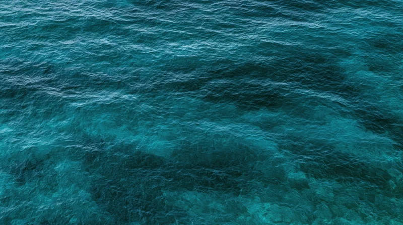 Aerial top-down view of open ocean surface filling the entire frame with rippling blue water