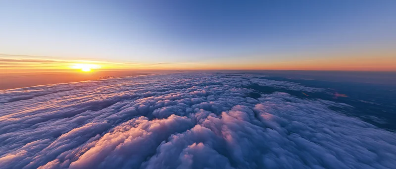 Aerial view above dense cloud layer at sunrise with sun on horizon