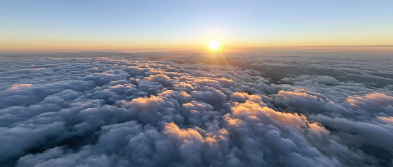 Aerial view of a vast cloud layer at sunrise from above the clouds