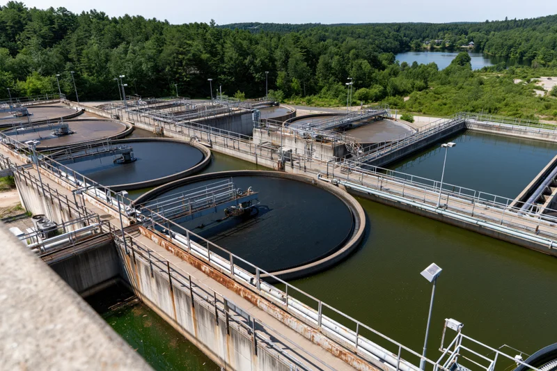 Aerial view of a wastewater treatment facility with circular tanks and surrounding greenery