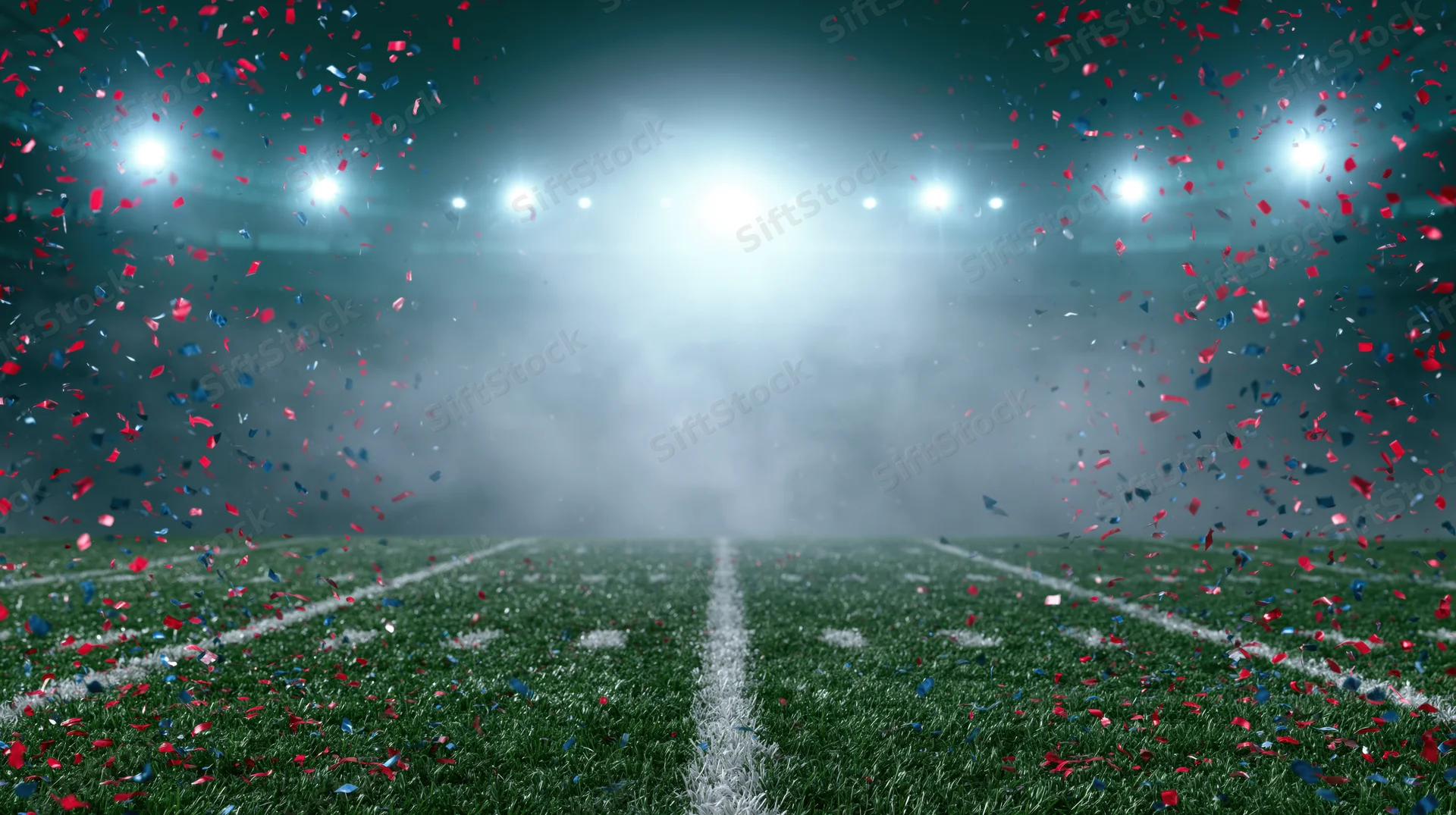 Football field at ground level with confetti falling under stadium lights at night