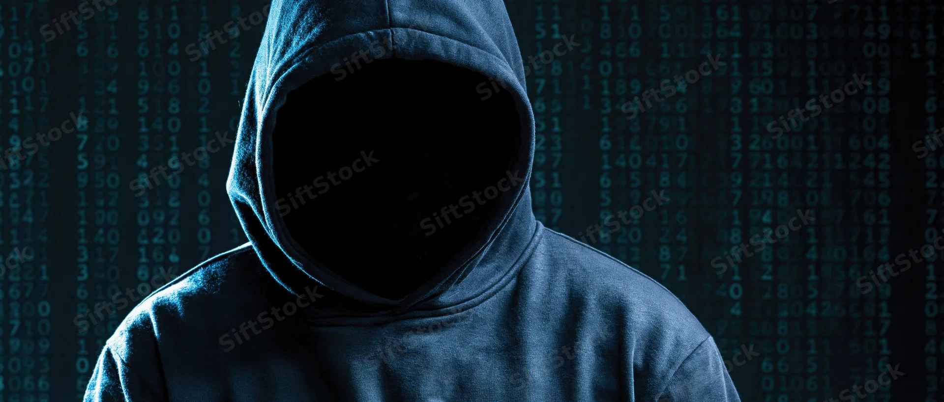 Hooded figure with hidden face standing before digital code display