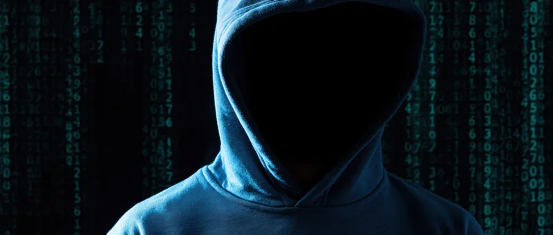 Hooded figure in silhouette against digital code background
