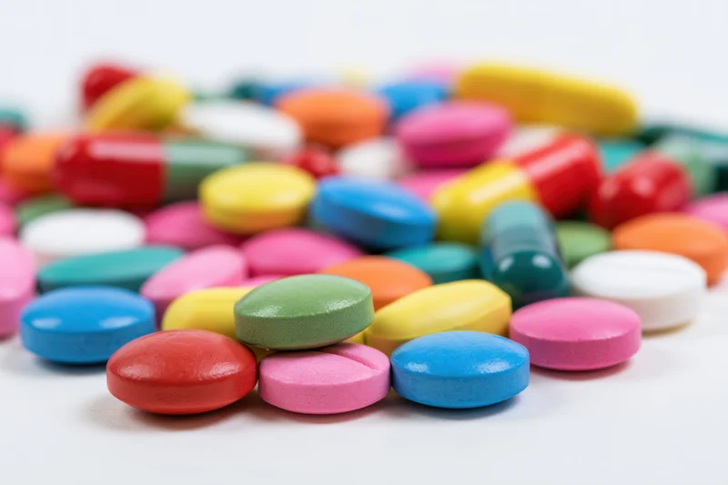 Colorful prescription pills and capsules scattered on a white surface
