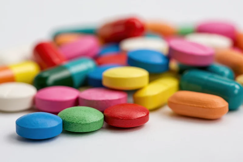 Colorful prescription pills and capsules scattered on a white surface