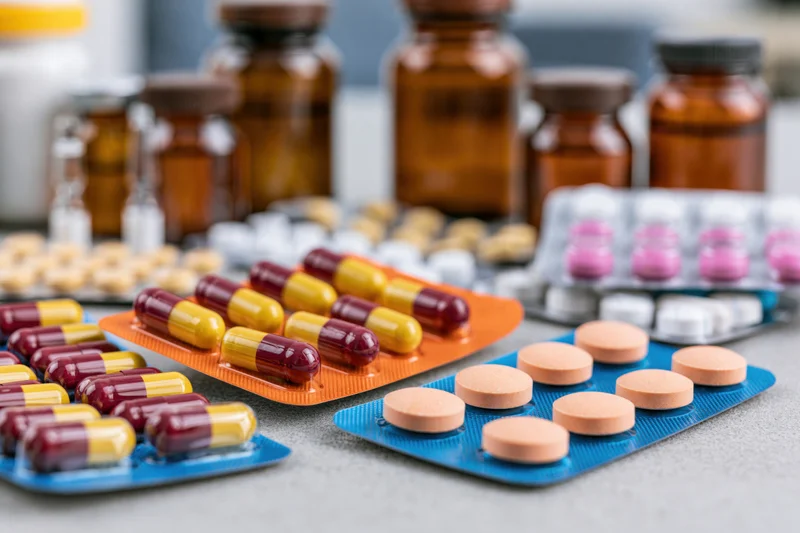Assorted pharmaceutical medications in blister packs and bottles arranged on a flat surface