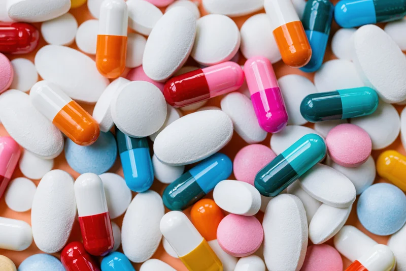 Assorted pharmaceutical pills and capsules scattered across a surface in a flat lay view