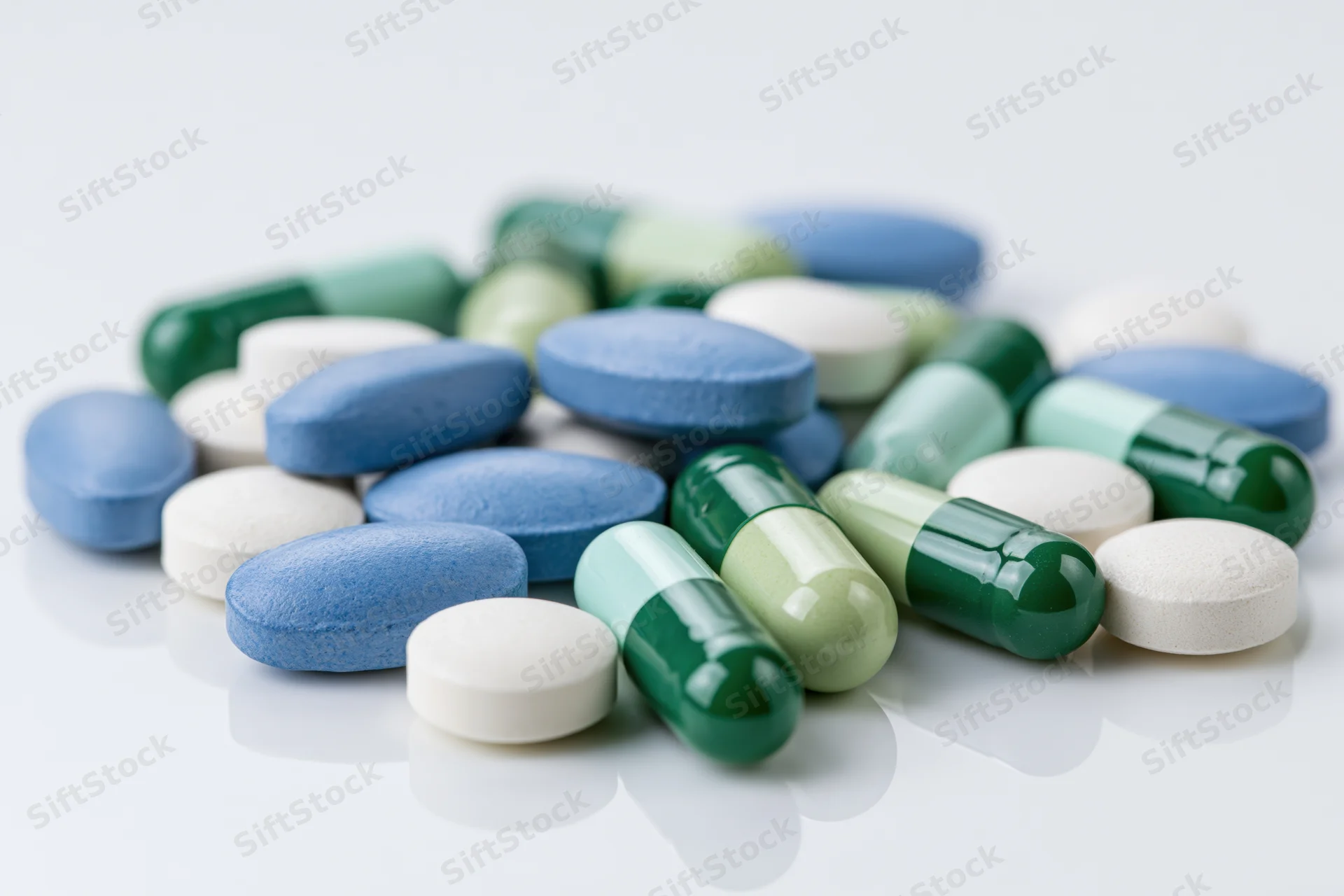 Assorted pharmaceutical pills and capsules scattered on a white surface