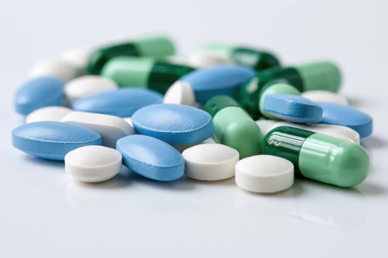 Assorted pharmaceutical pills and capsules scattered on a white surface