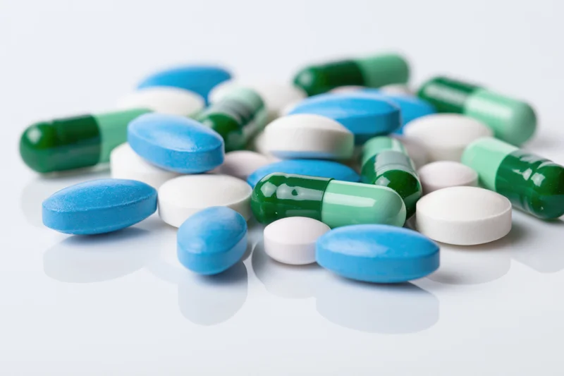 Assorted pharmaceutical pills and capsules scattered on a white surface