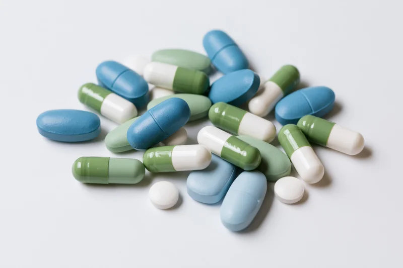 Assorted pharmaceutical pills and capsules scattered on a white surface