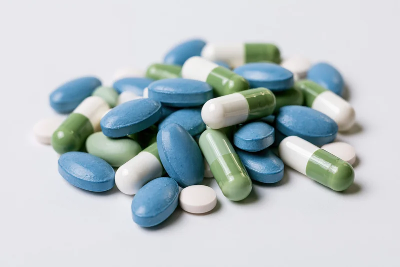 Assorted pharmaceutical pills and capsules scattered on a white surface