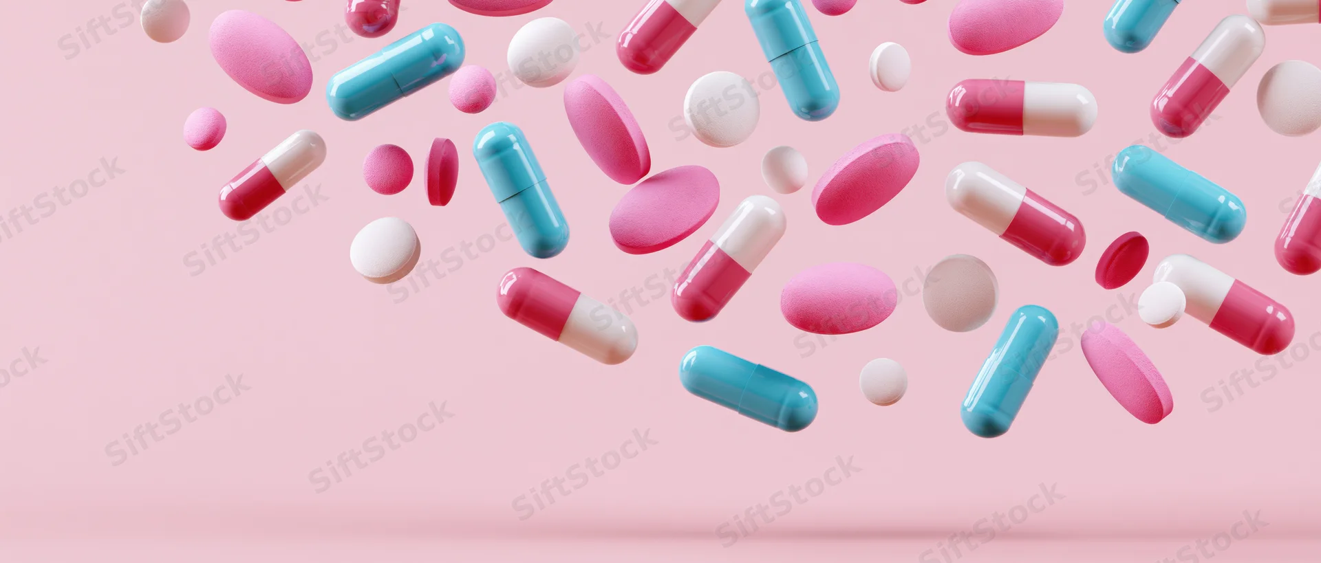 Assorted pharmaceutical pills and capsules floating mid-air against a pink background