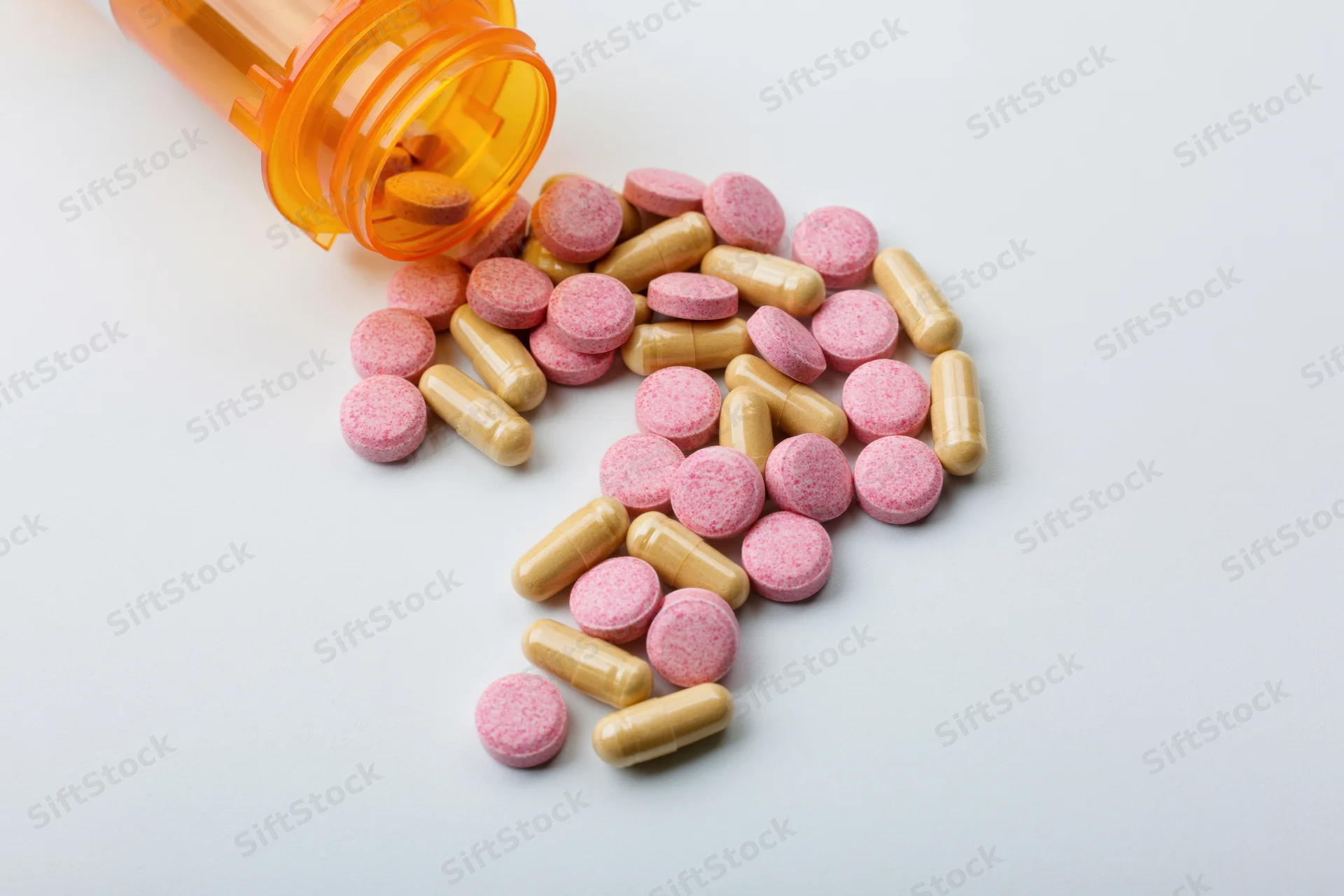 Assorted pills and capsules scattered in shape of question mark on white surface