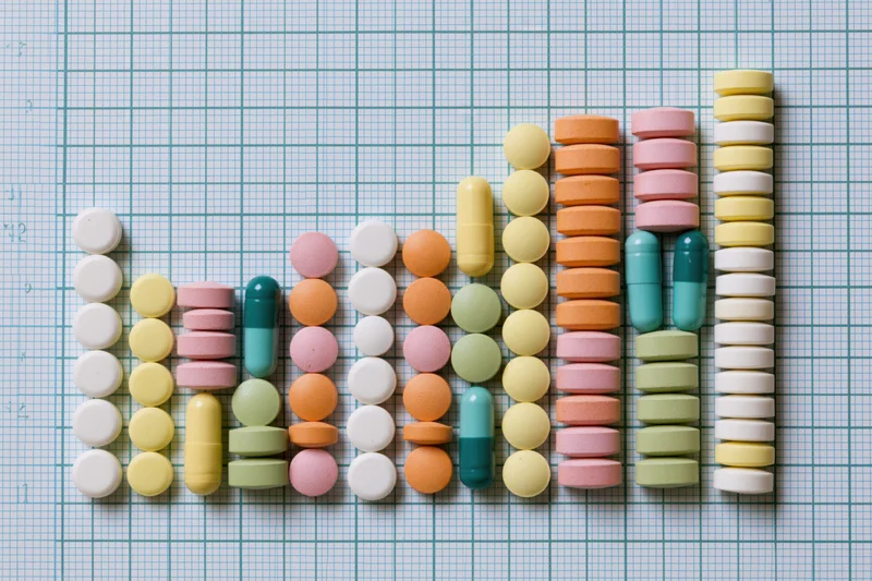 Colorful pills and capsules arranged in rising columns on graph paper
