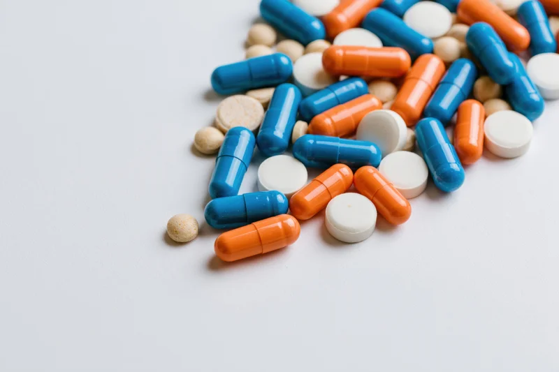 Assorted medication capsules and tablets scattered on a white surface