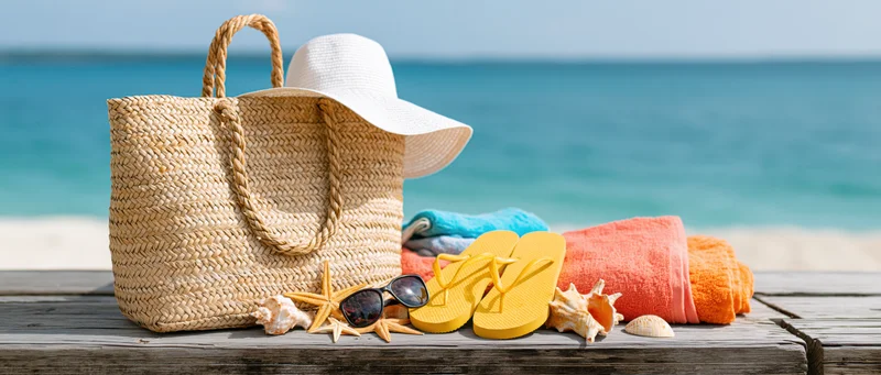 Beach vacation accessories arranged on wooden deck near ocean