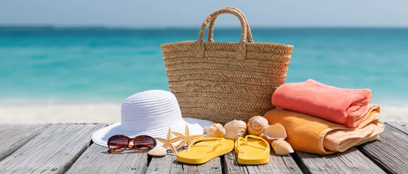 Beach vacation accessories arranged on wooden deck near ocean