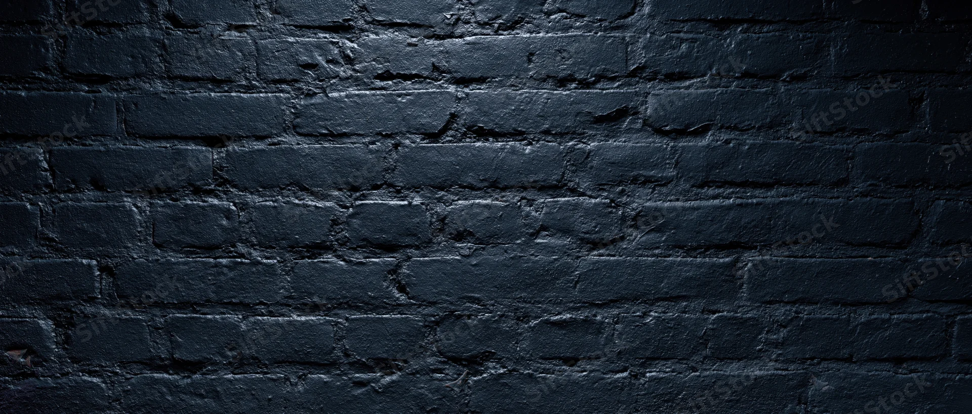 Black-painted brick wall filling the frame with textured surface and shadowed details