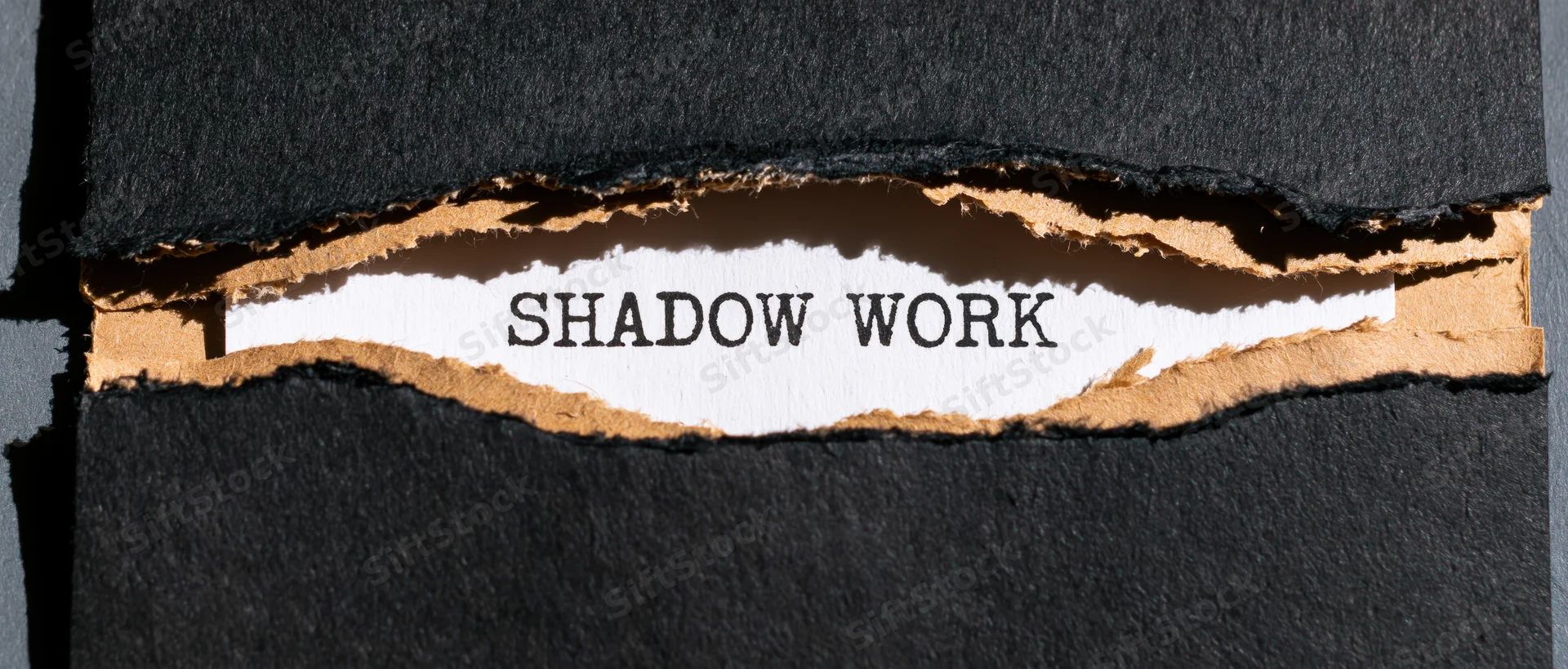 Torn black cardboard revealing the words shadow work on white paper beneath