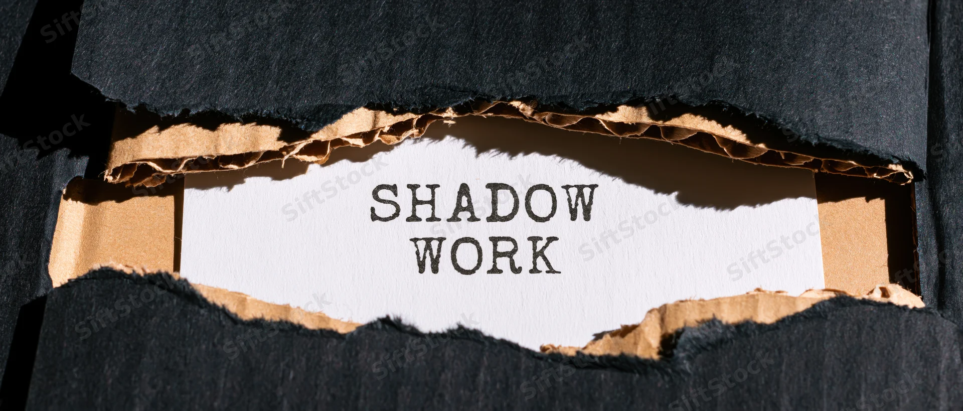 Torn black cardboard revealing the words shadow work on white paper beneath
