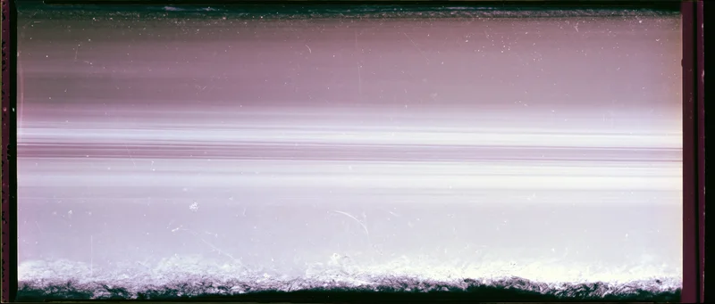 Overexposed 35mm film frame with light leak and damage showing purple and white gradients and scratches
