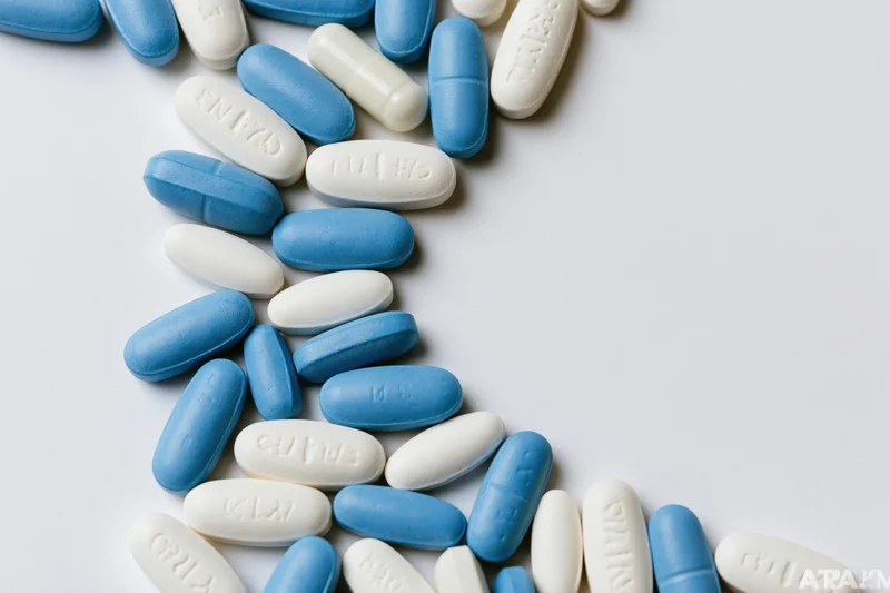 Blue and white oval pills scattered along the left edge on a white surface