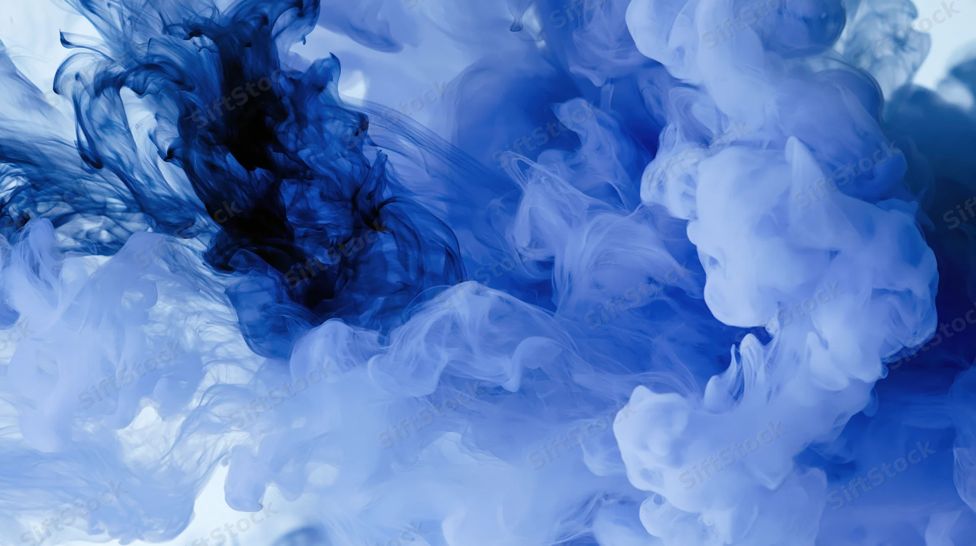 Blue ink dispersing in water creating abstract swirling patterns