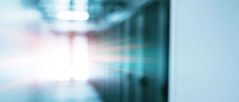 Blurred view of a server room corridor with glowing lights and racks lining the walls