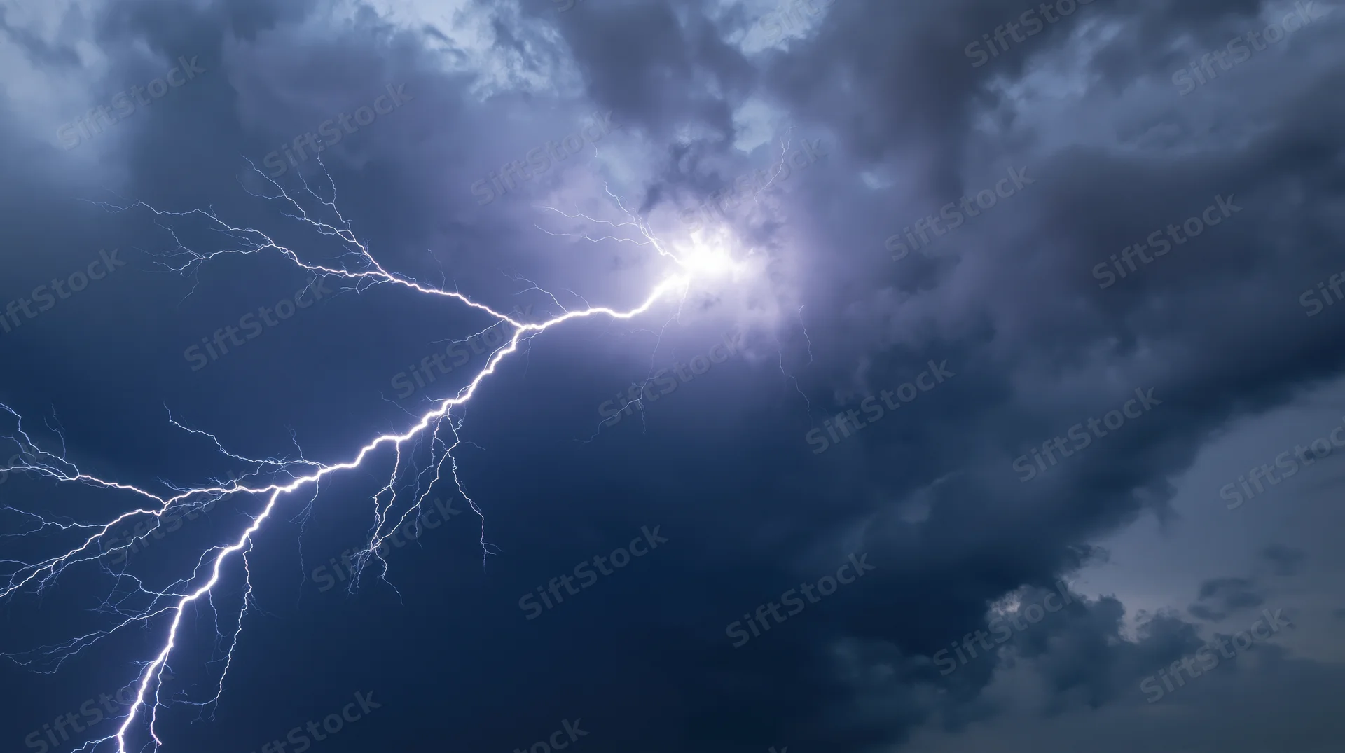 Bright lightning bolt splitting across a dark stormy sky at night