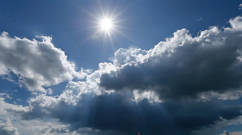 Bright sun shining through dramatic cumulus clouds in a blue sky