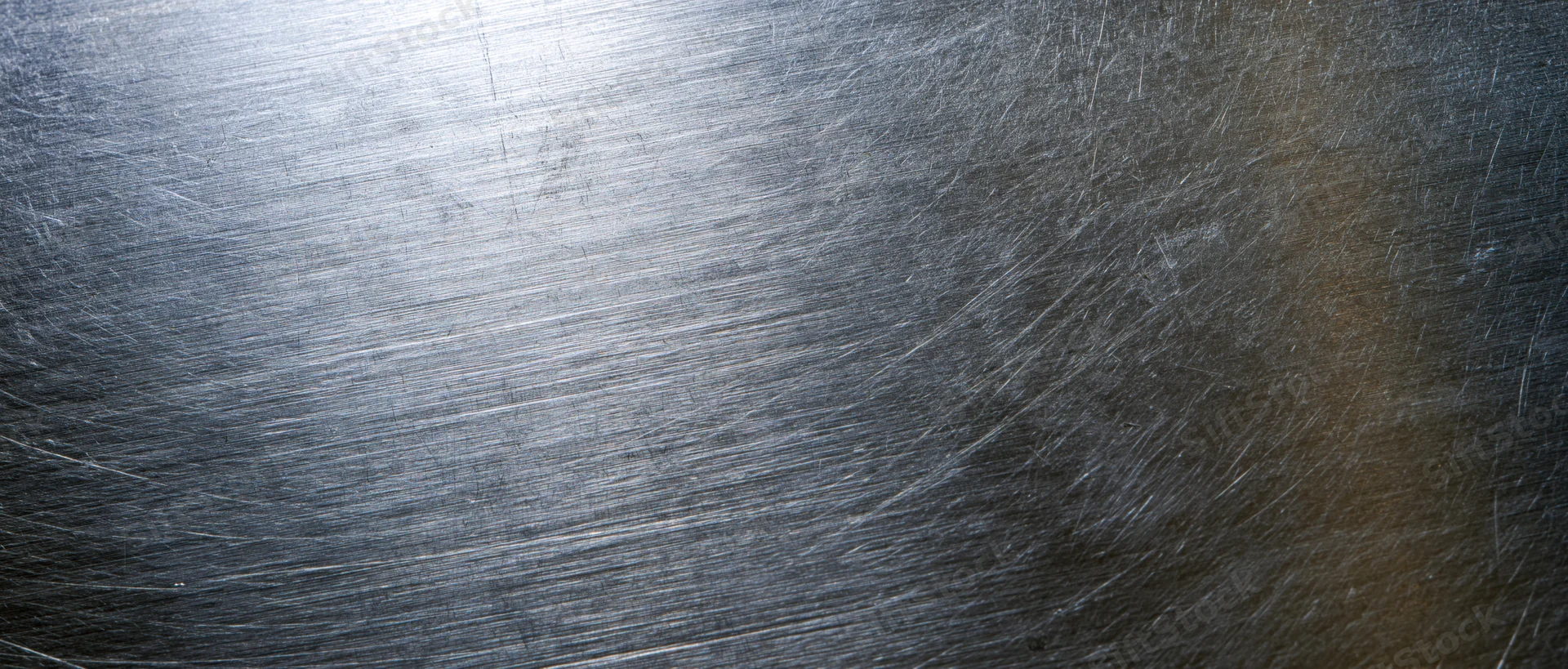 Brushed stainless steel surface with linear texture and reflective highlights filling the frame