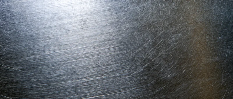 Brushed stainless steel surface with linear texture and reflective highlights filling the frame