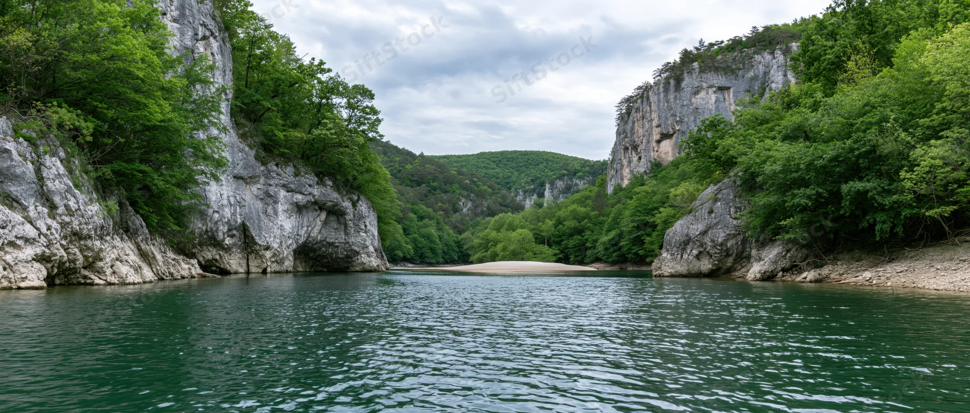 Calm river flowing through a narrow canyon framed by steep limestone cliffs and dense green forest