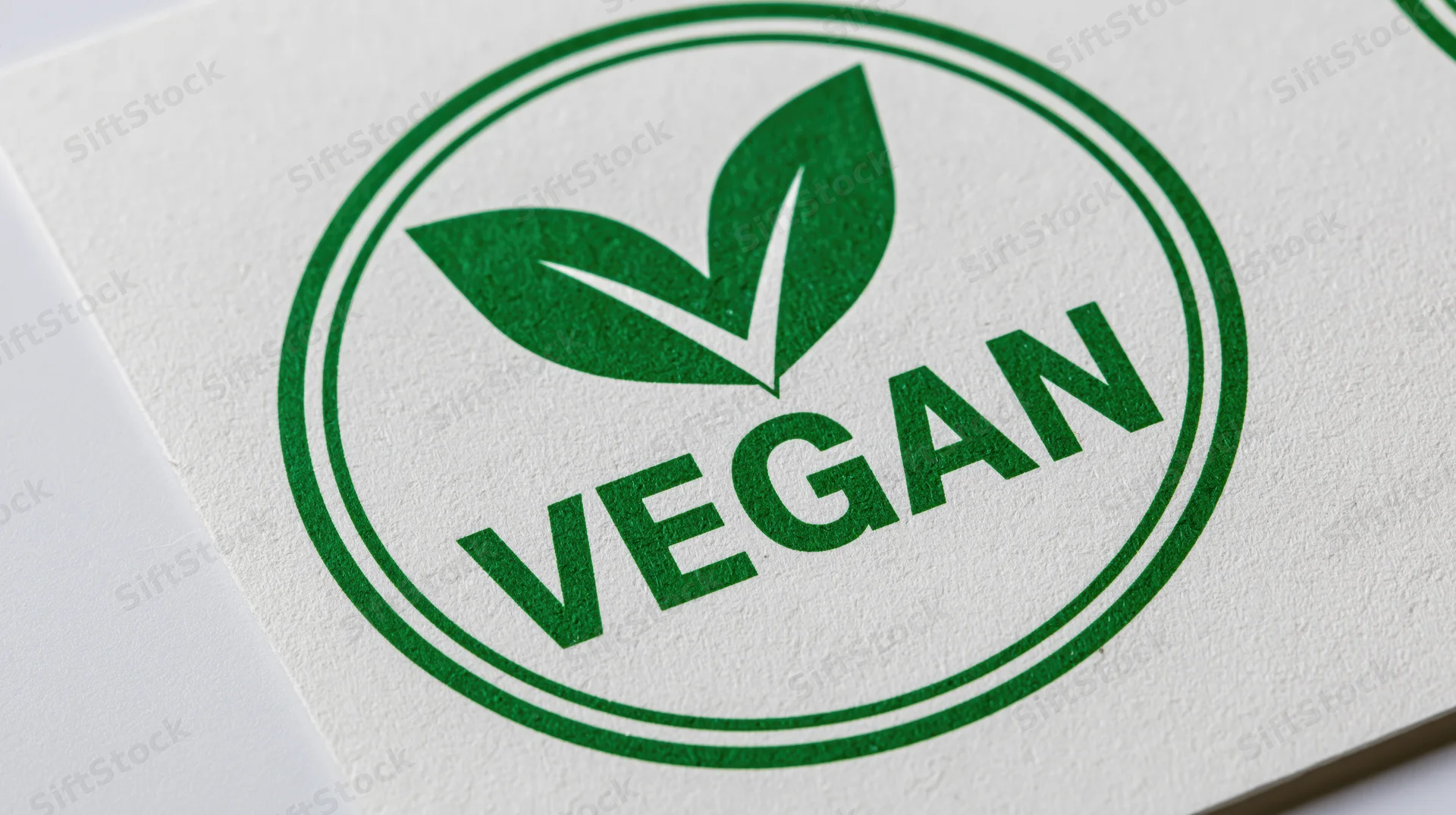 Circular green vegan certification badge printed on white textured paper