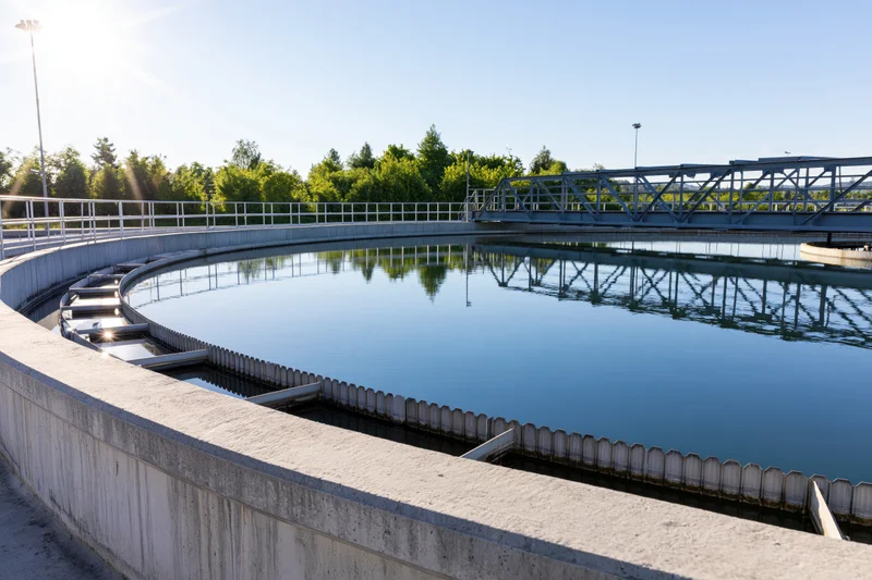 Circular clarifier tank in a municipal wastewater treatment facility under sunlight